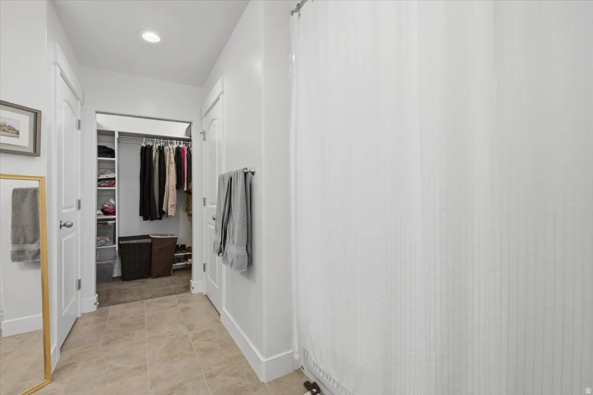 Walk-in closet with built-in shelving and hanging rods, recessed lighting, and tile flooring