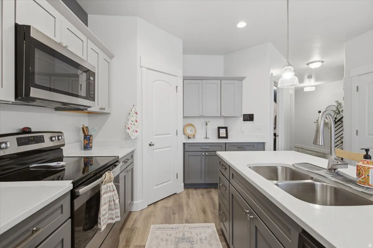Two-tone cabinetry with light countertops, stainless steel appliances, and wood-finish flooring