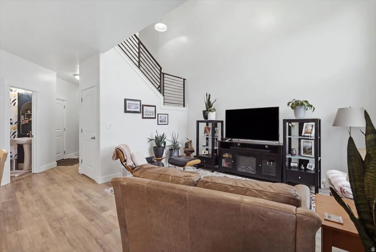Expansive living area featuring high ceilings, wood-finish flooring, and a modern stair railing