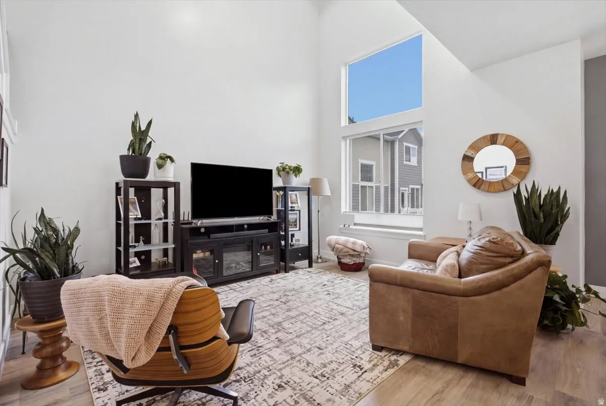 Vaulted ceilings, large windows, light wood-finish flooring, white walls, and built-in shelving