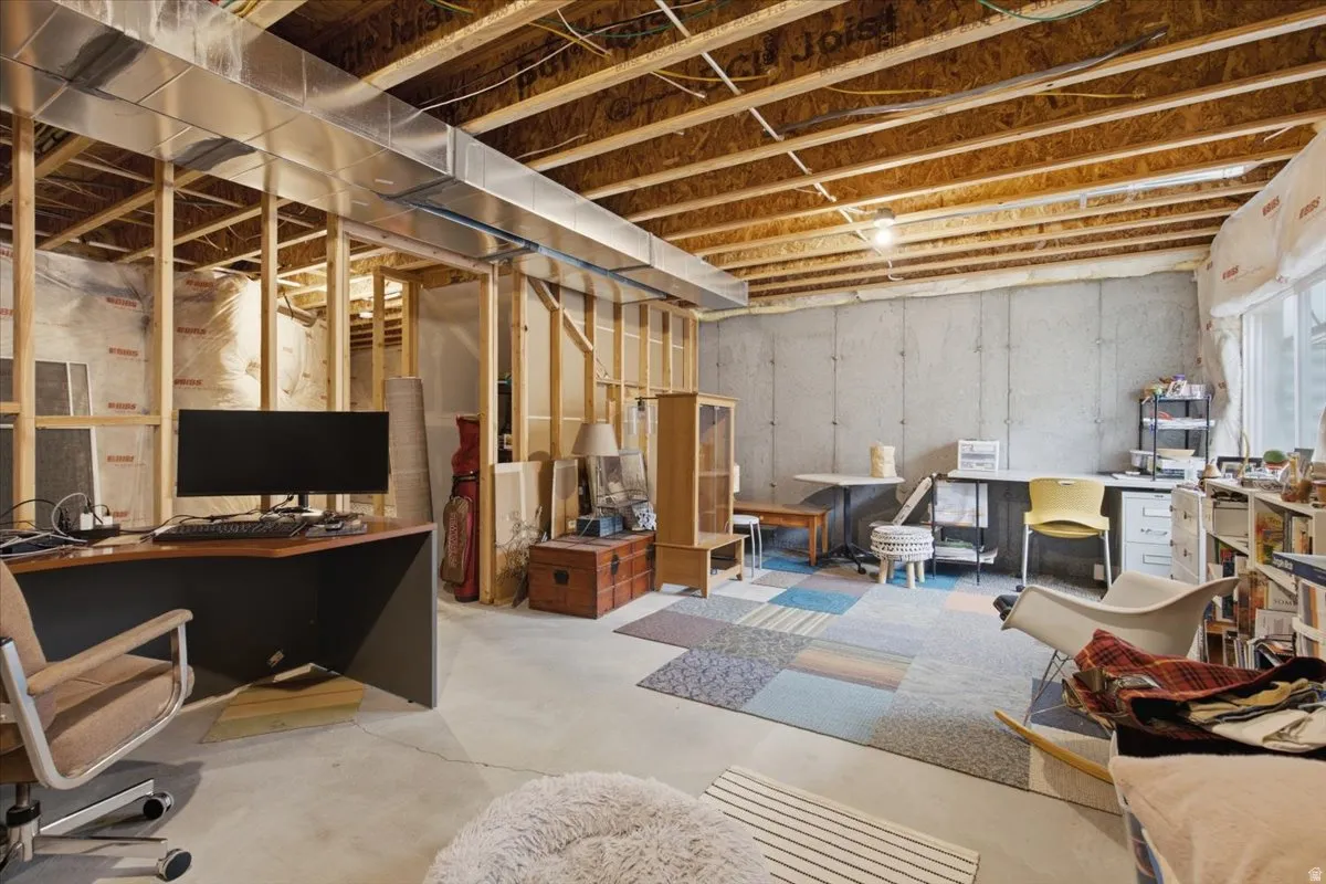 Unfinished basement featuring exposed wood joists, concrete walls, and framed interior walls