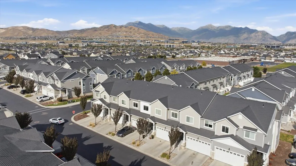 Townhome community with multiple architectural styles, pitched roofs, attached garages, and landscaping