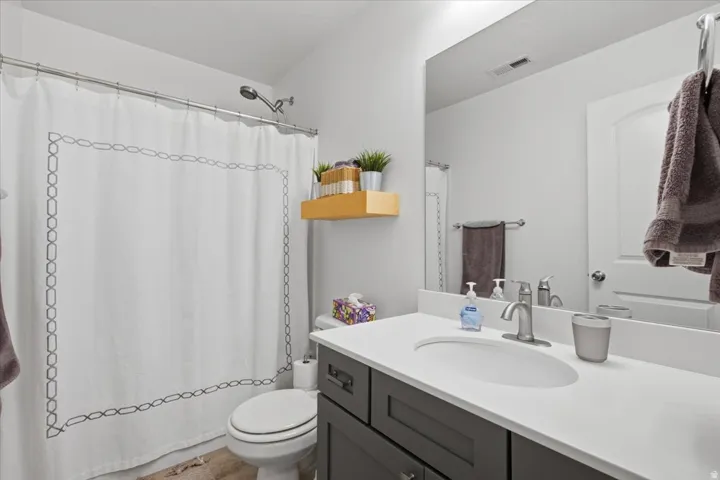 Bathroom featuring a full vanity with an integrated sink, brushed nickel faucet, large mirror, and a shower with a chrome showerhead