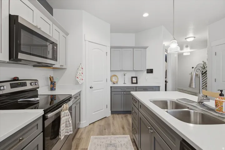 Two-tone cabinetry with light countertops, stainless steel appliances, and wood-finish flooring