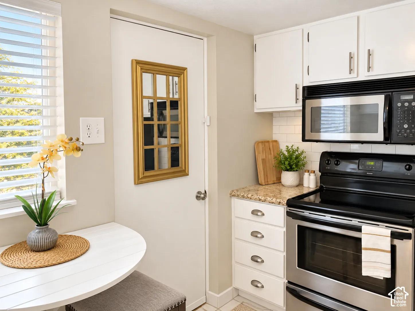 White shaker-style cabinetry with chrome hardware, subway tile backsplash, and stone-finish countertops