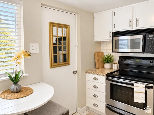 White shaker-style cabinetry with chrome hardware, subway tile backsplash, and stone-finish countertops