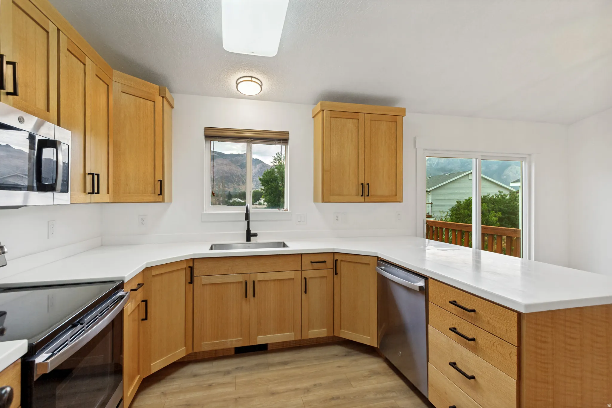 Kitchen featuring wood-finish cabinetry, stainless steel appliances, white countertops, and wood-finish flooring