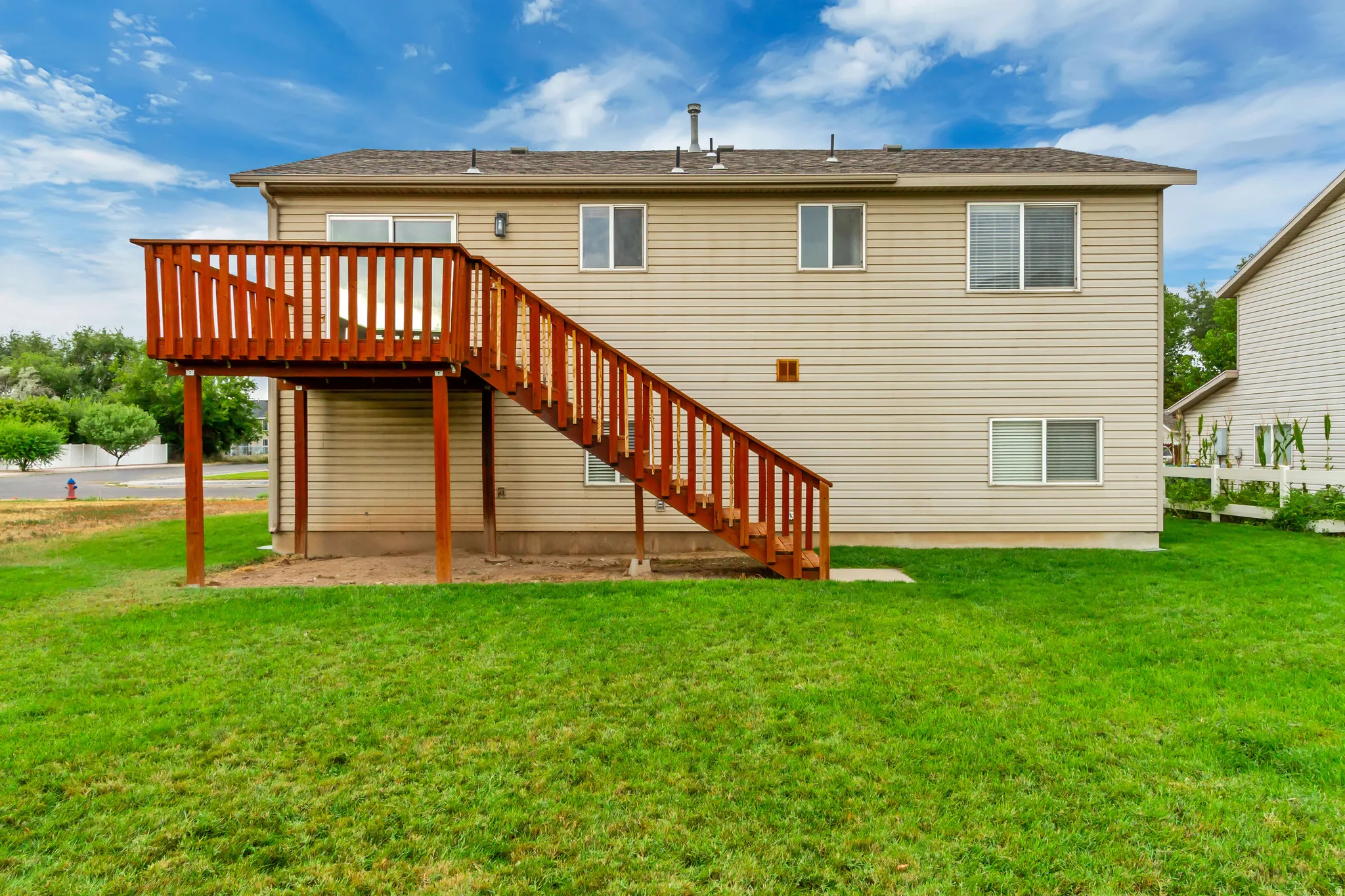 Rear exterior with a wooden deck and staircase, siding finish, and multiple windows