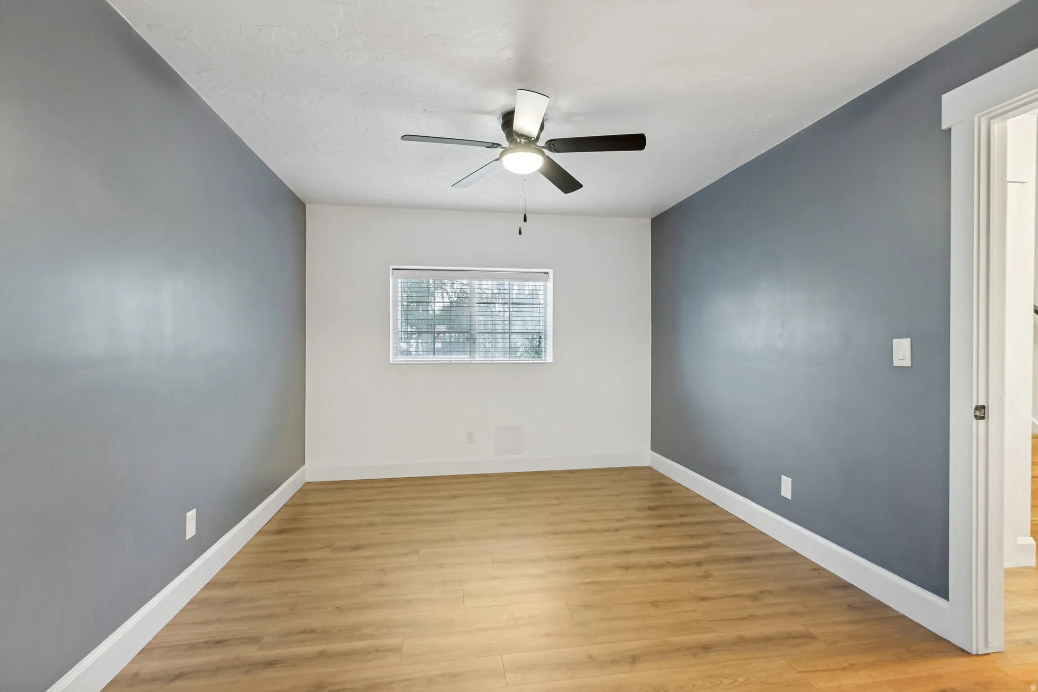 Wood-finish flooring, a ceiling fan, and a window with horizontal blinds