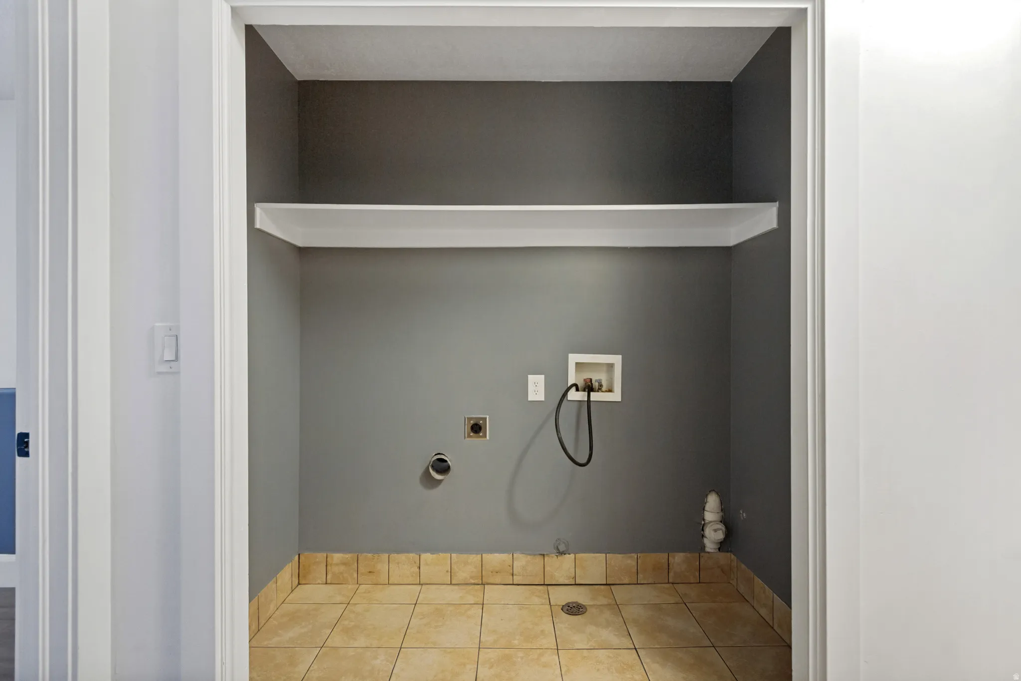 Laundry area with tile flooring, a built-in shelf, and utility hookups
