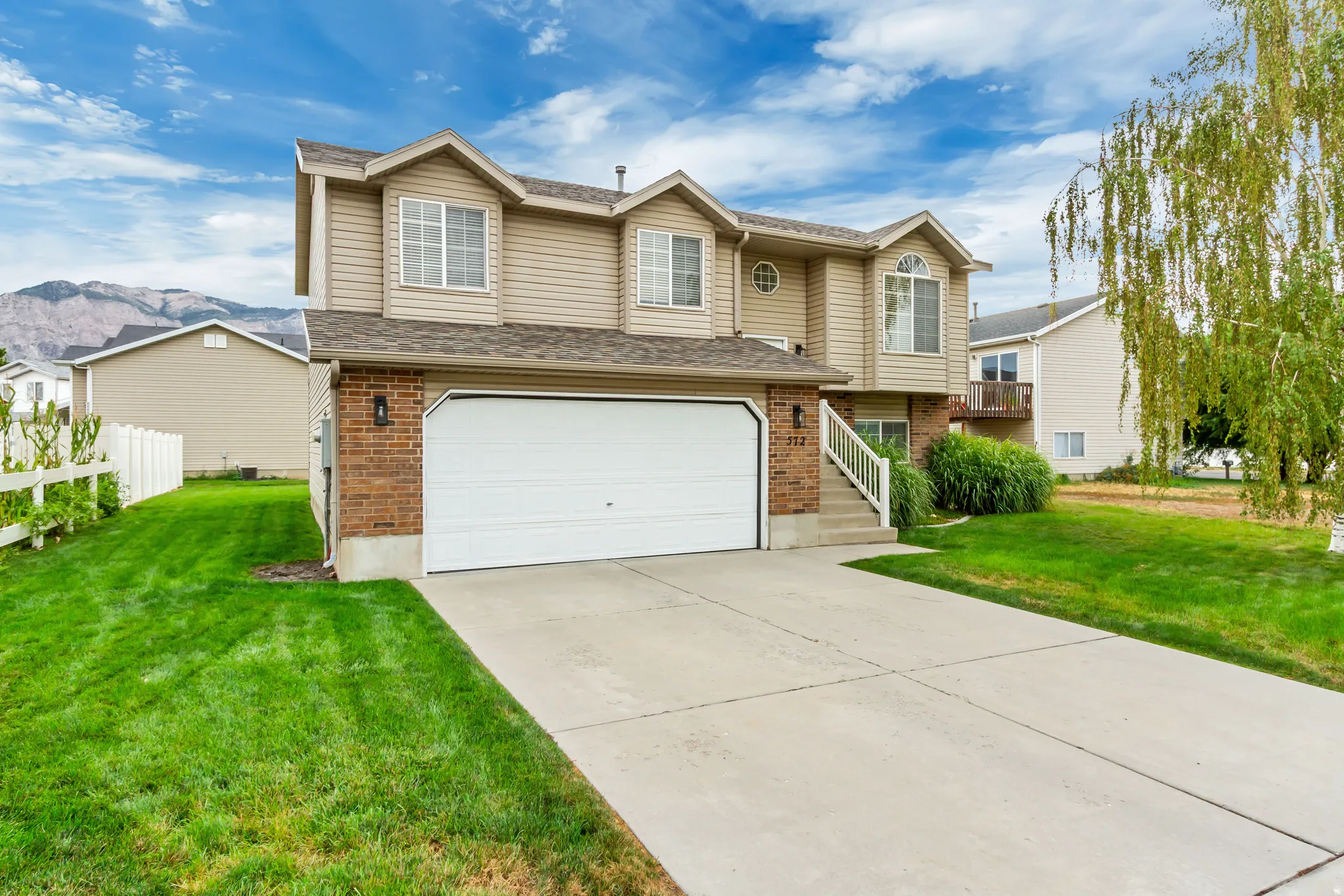 Two-story residence featuring a two-car garage, partial brick facade, and a concrete driveway