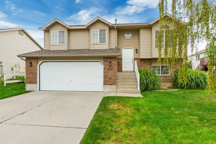 Two-story residence featuring brick and siding exterior, an attached two-car garage, concrete driveway, and front lawn with mature landscaping