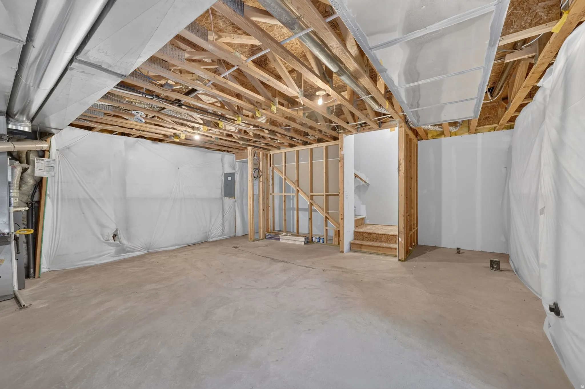 Unfinished lower level featuring exposed wood joists, concrete flooring, and partial wall framing