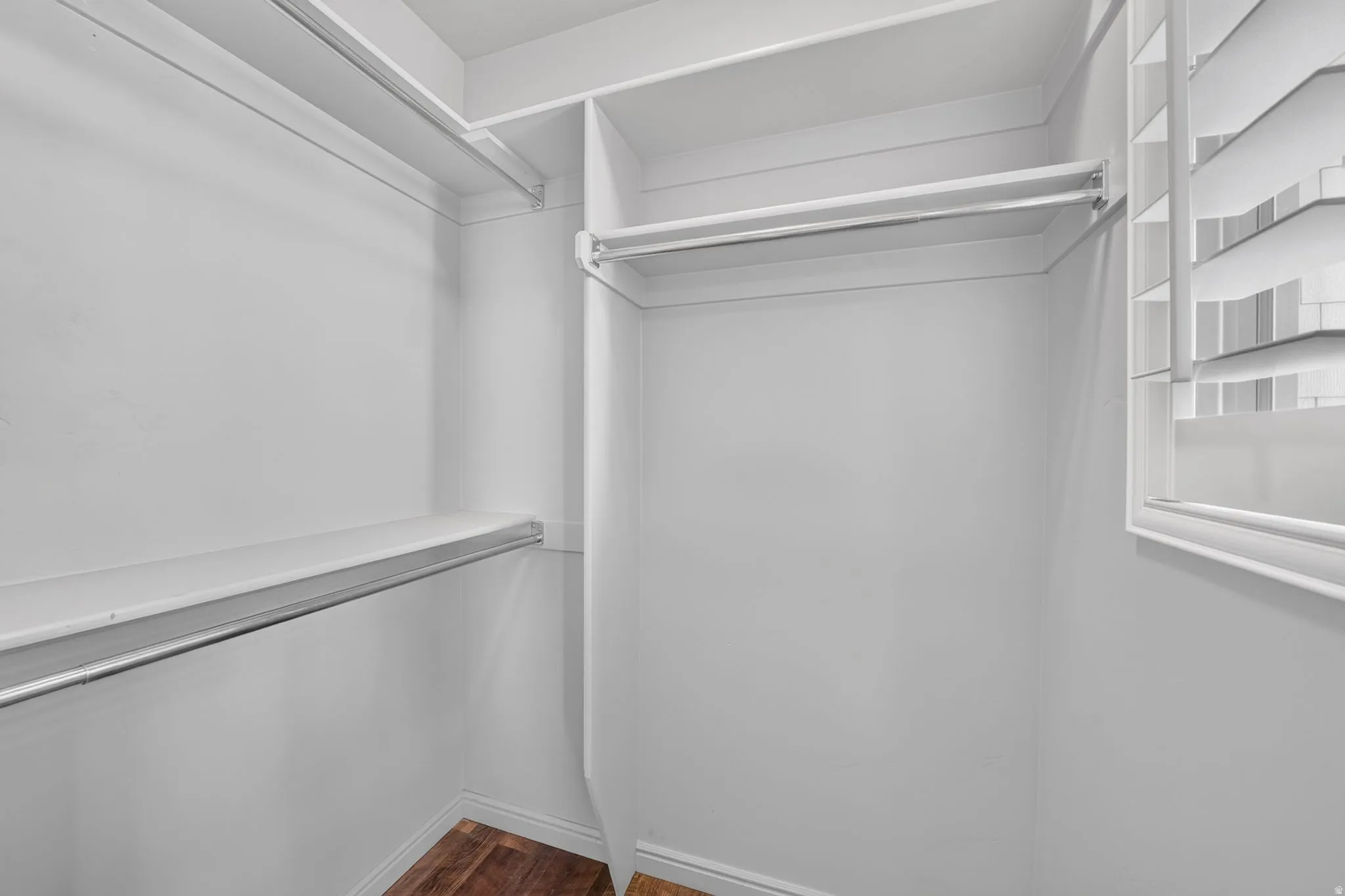 Built-in closet shelving, hanging rods, wood-finish flooring, and a window with louvered blinds