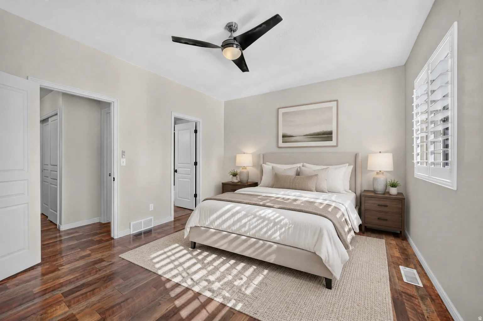 Hardwood-finish flooring, a ceiling fan with integrated lighting, and a window with plantation shutters