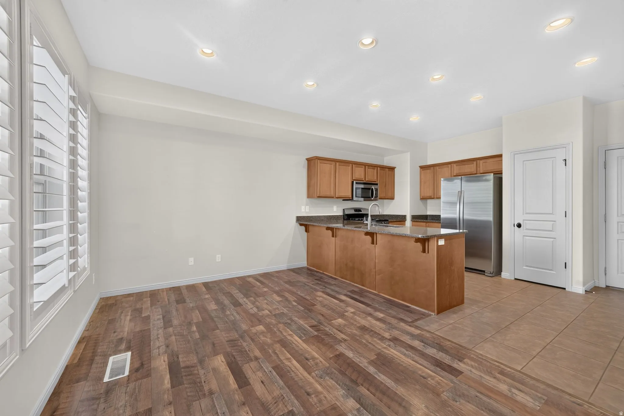 Kitchen with wood-finish cabinetry, stainless steel appliances, and a breakfast bar