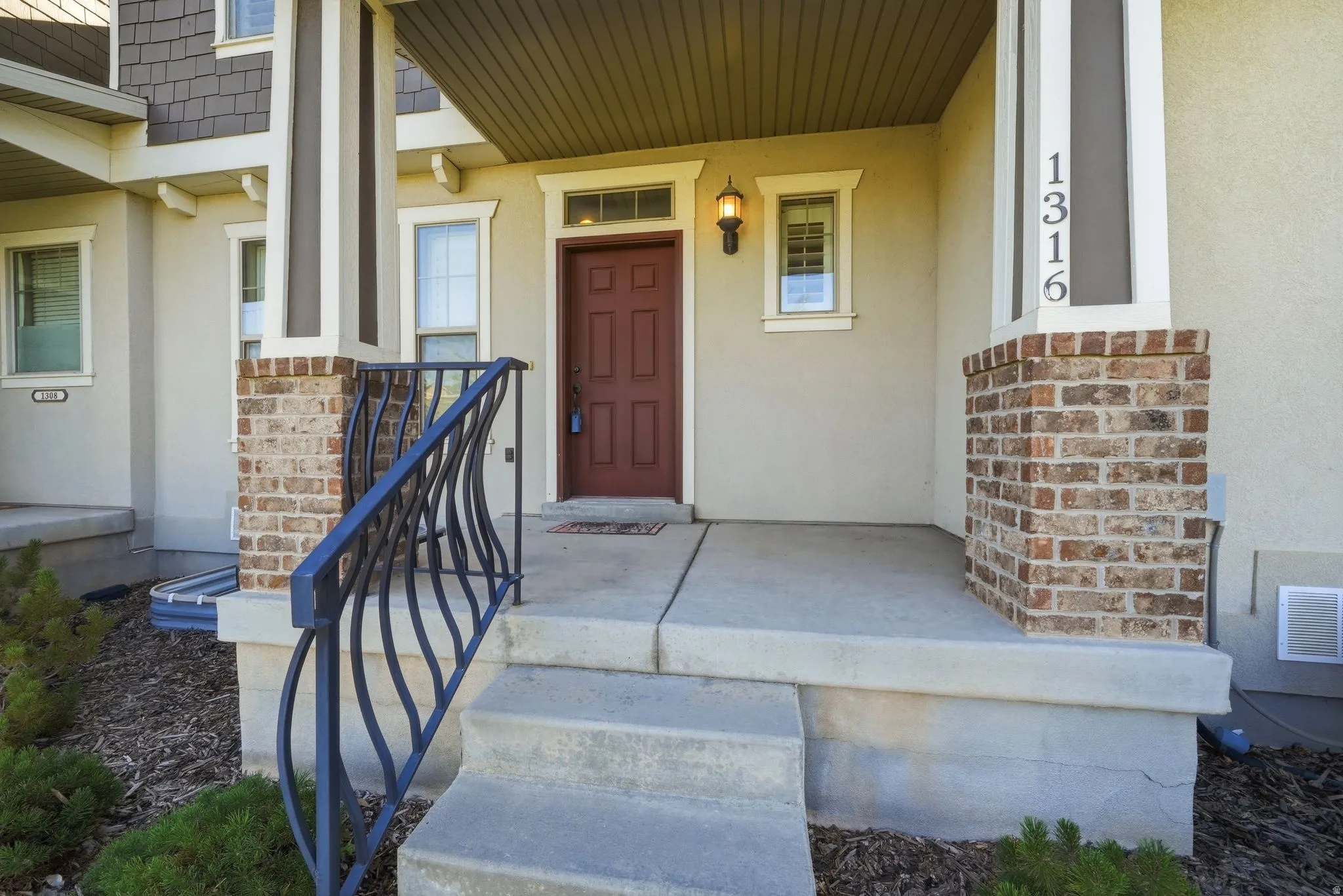 Entry featuring a rich wood-finish door, sconce lighting, and decorative iron railing