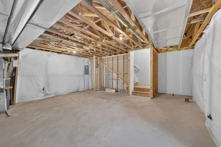 Unfinished lower level featuring exposed wood joists, concrete flooring, and partial wall framing