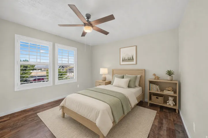 Dual windows with white framing, wood-finish flooring, and a ceiling fan with integrated lighting
