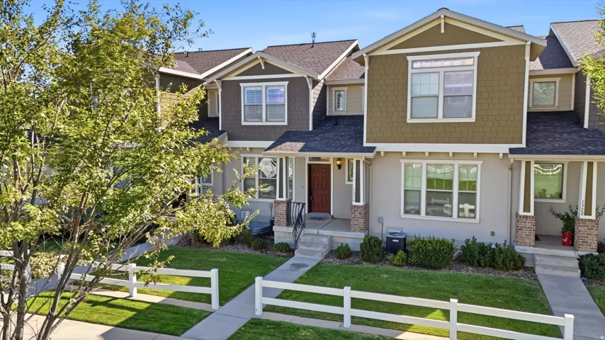 Townhome exterior featuring varied siding textures, a covered front entry, and a white picket fence