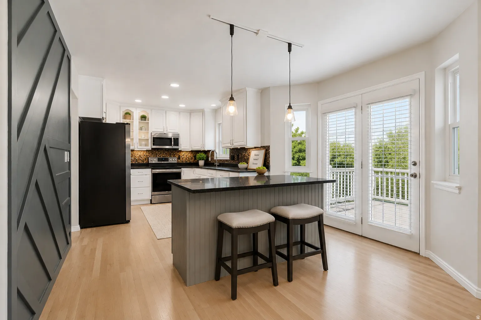 Open kitchen and dining area, French doors to large valley-view deck, kitchen island, abundant cabinets and counter space, large windows, custom decorative wall, and plenty of natural light