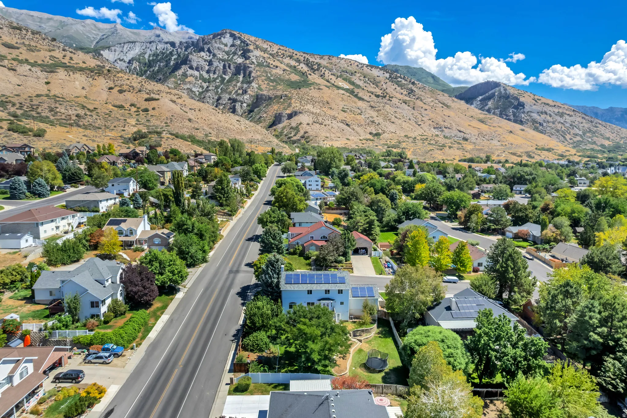 Residential neighborhood with mature trees situated at the base of a mountain range