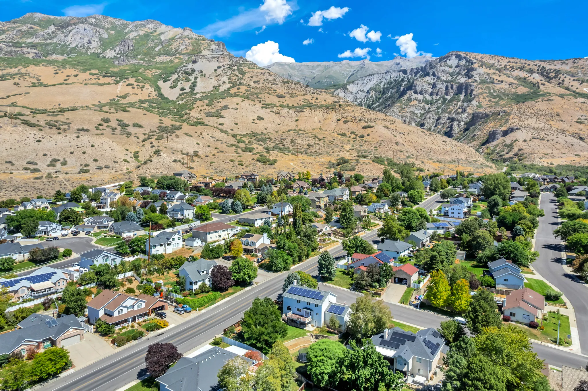 Aerial perspective showcasing a residential neighborhood with mountain backdrops, established homes, and mature trees