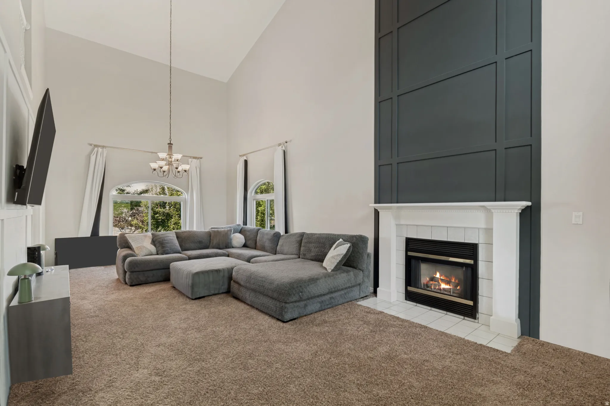 Impressive great room featuring vaulted ceilings, striking modern decorative trim, large windows for lots of natural light and a cozy fireplace for relaxing and entertaining