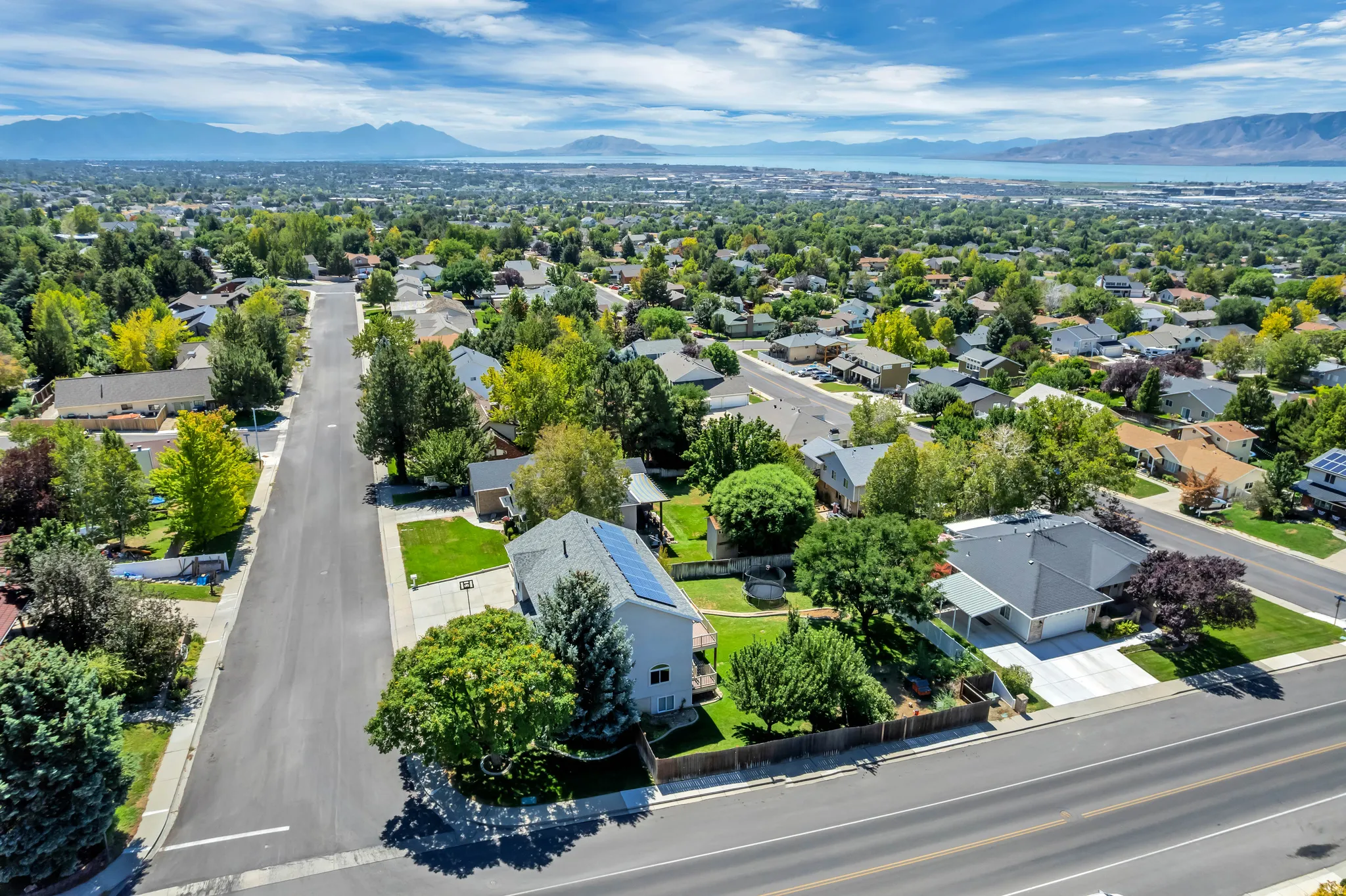 Neighborhood setting with mature trees and a distant lake and mountain backdrop