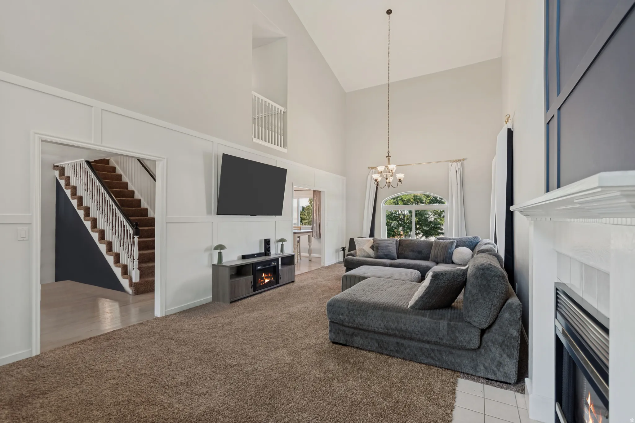 Impressive great room featuring vaulted ceilings, striking modern decorative trim, large windows for lots of natural light and a cozy fireplace for relaxing and entertaining