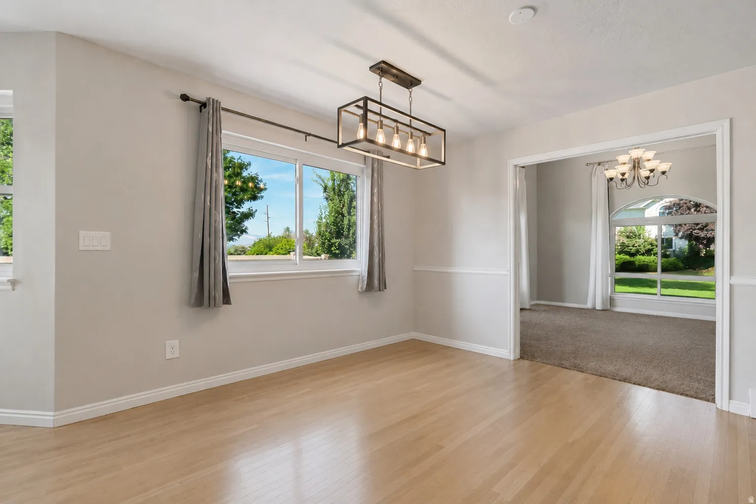 Open kitchen and dining area, French doors to large valley-view deck, kitchen island, abundant cabinets and counter space, large windows, custom decorative wall, and plenty of natural light