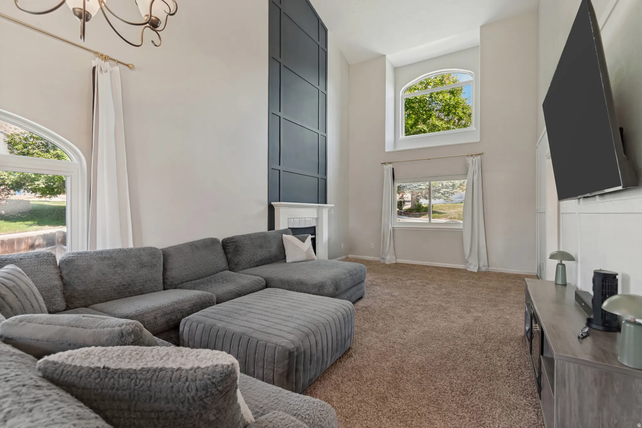 Impressive great room featuring vaulted ceilings, striking modern decorative trim, large windows for lots of natural light and a cozy fireplace for relaxing and entertaining