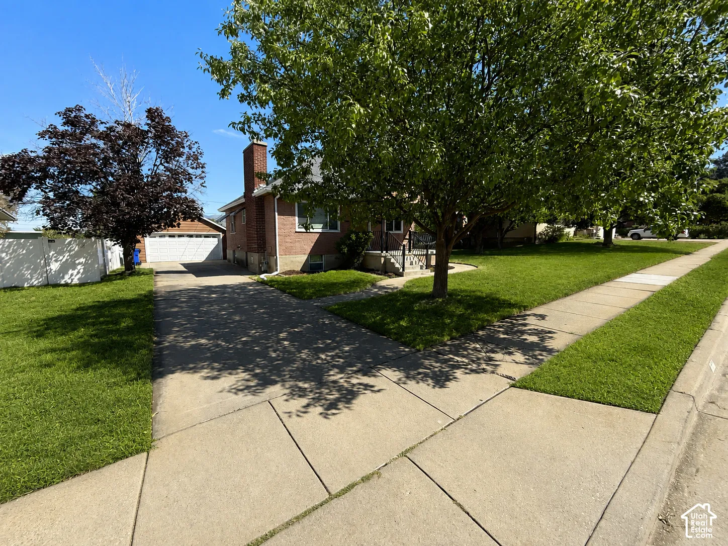 Brick exterior residence featuring a concrete driveway, a sidewalk, and a detached two-car garage