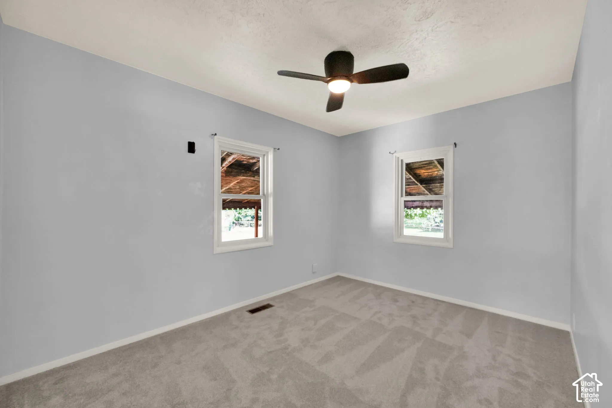 Soft gray carpeting with white trim, light blue walls, and a ceiling fan
