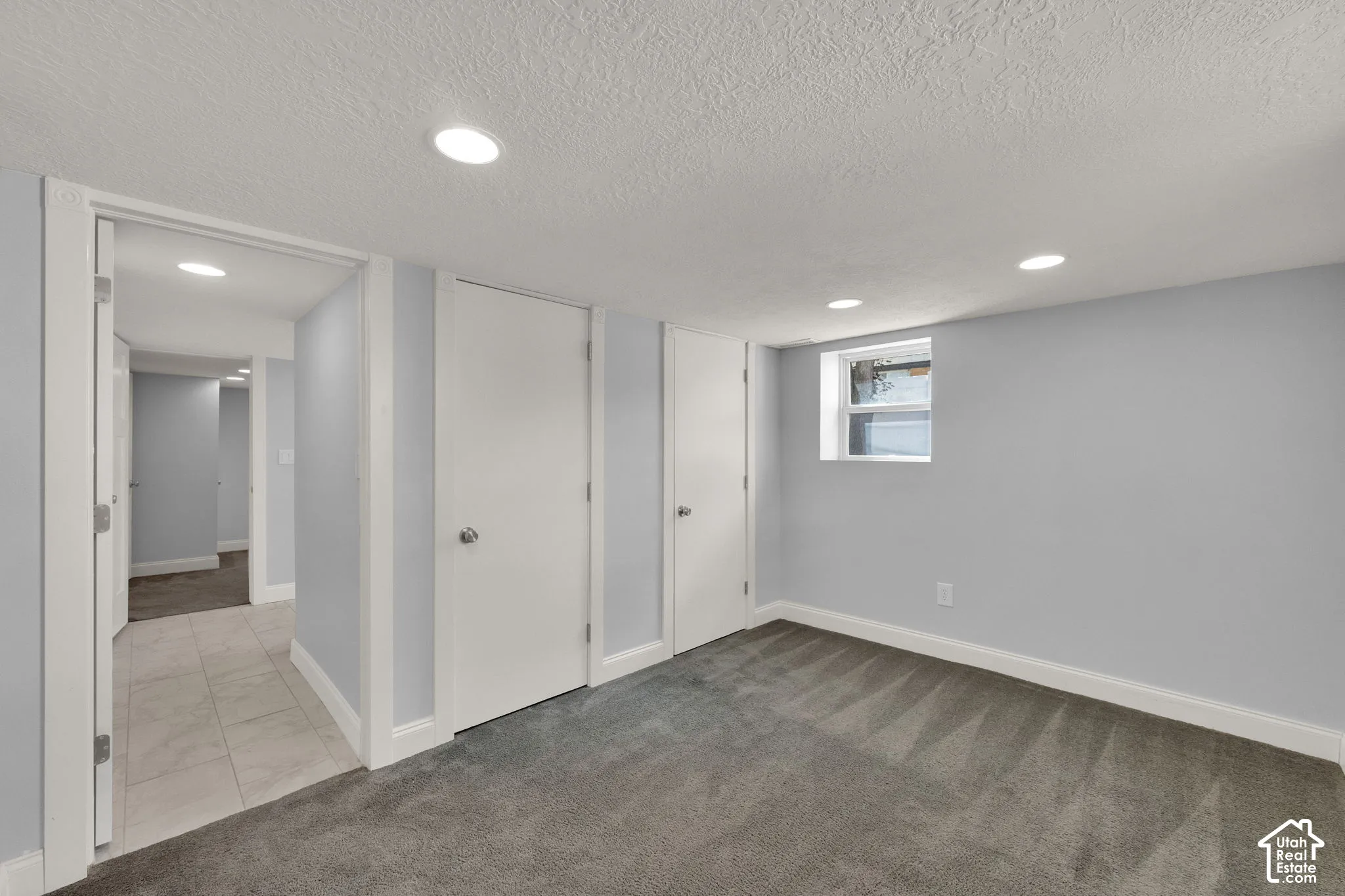 Recessed lighting, gray carpeting, a single window, and white trim accents