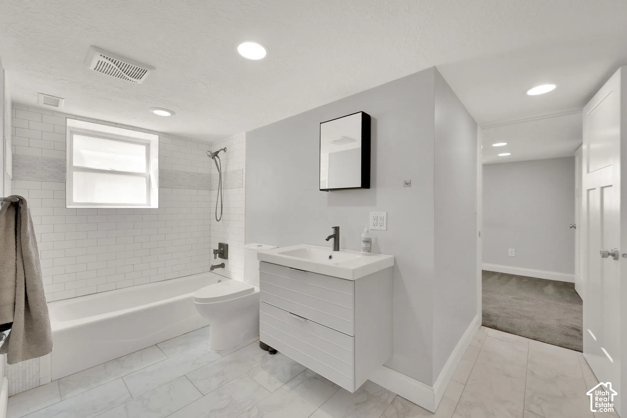 Bathroom featuring a soaking tub with subway tile surround, a modern vanity with integrated sink, and recessed lighting