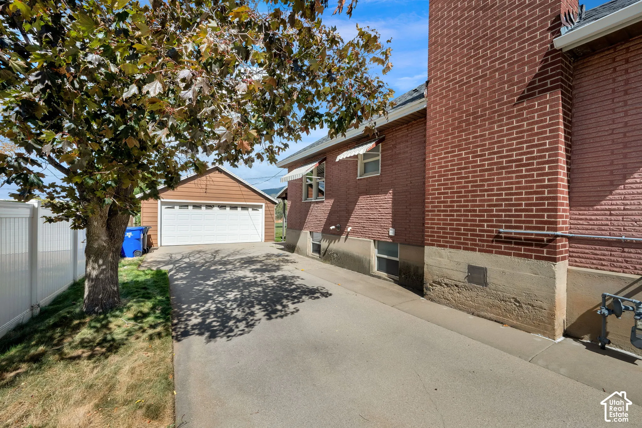Brick exterior with concrete foundation, asphalt driveway, and detached garage with white paneled door