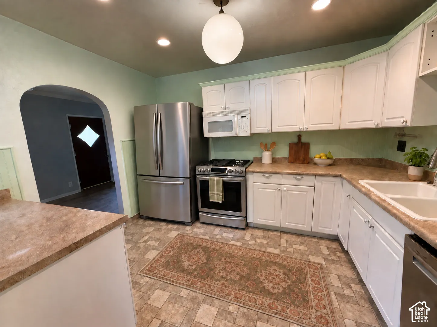 White cabinetry with stainless steel appliances, laminate countertops, and recessed lighting