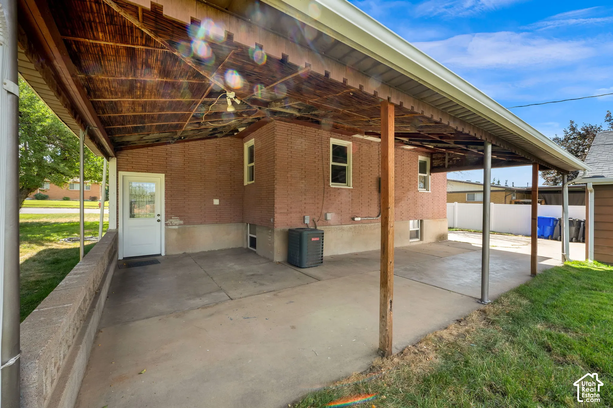 Covered concrete patio with wooden support beams and an exterior door