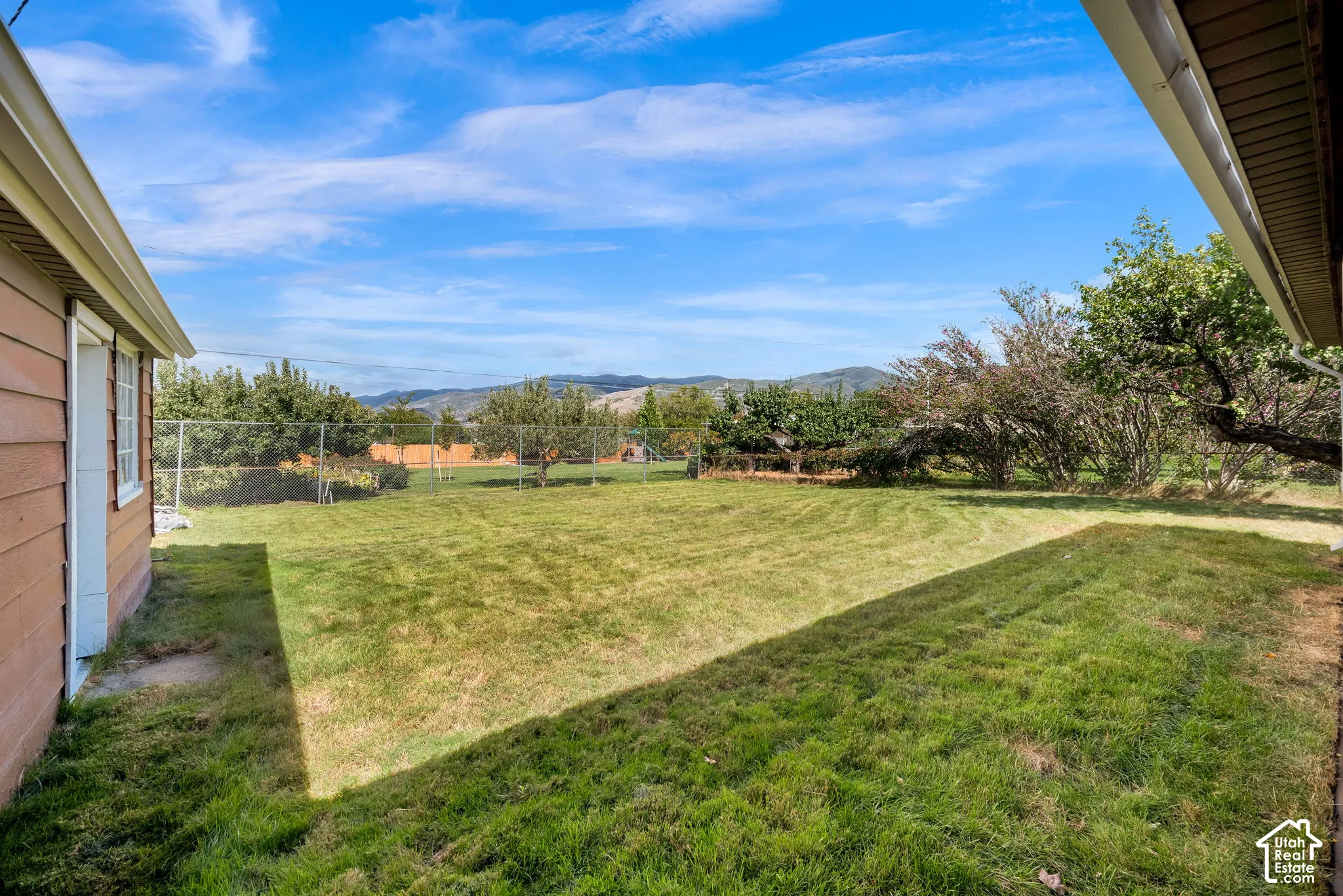 Expansive lawn featuring mature trees and chain-link fencing