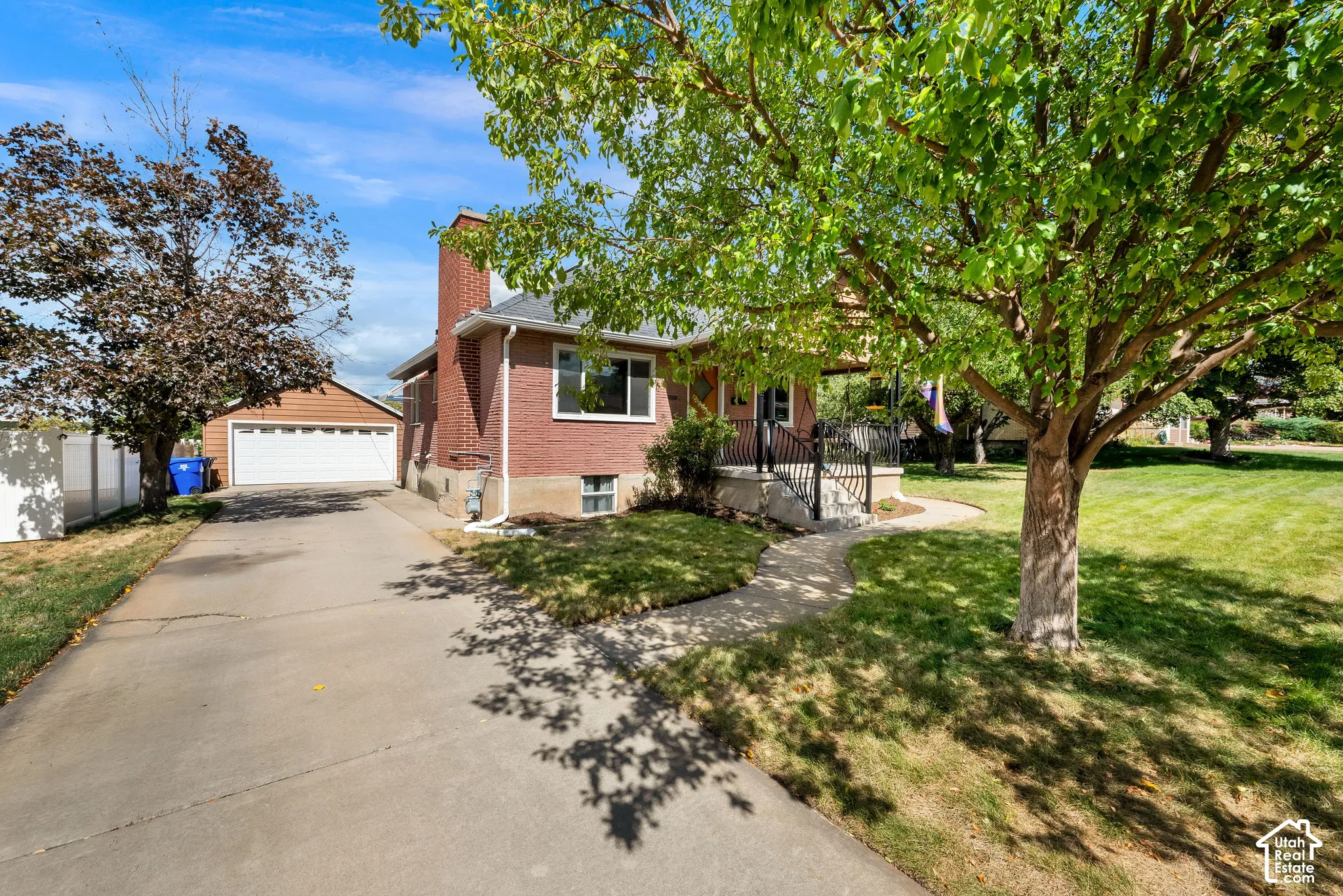 Brick exterior with a prominent chimney, a paved driveway, and an attached garage