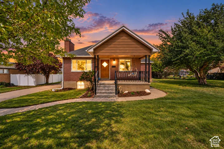 Brick exterior featuring a covered front porch, concrete steps, masonry chimney, and a diamond-pane entry door