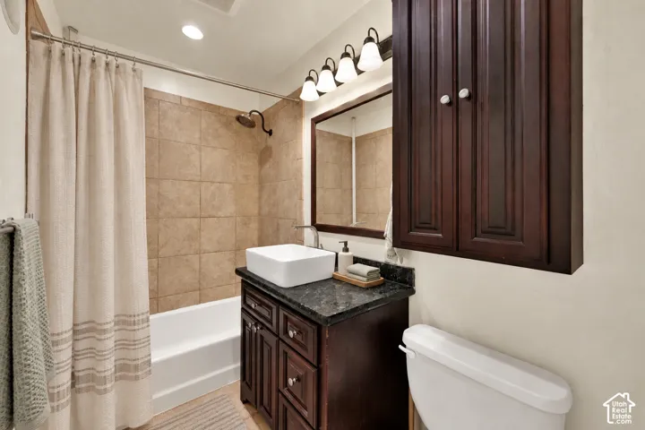 Bathroom featuring a tile shower surround, dark wood-finish vanity with a vessel sink, and a wall-mounted medicine cabinet