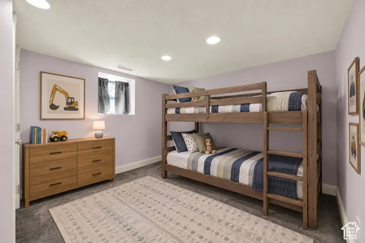 Recessed ceiling lighting, soft wall color, wood-finish dresser, and dark carpet