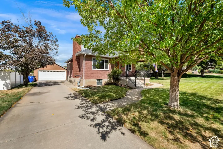 Brick exterior with a prominent chimney, a paved driveway, and an attached garage