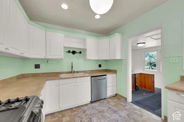 White cabinetry, light countertop surfaces, stainless steel dishwasher, and a built-in sink
