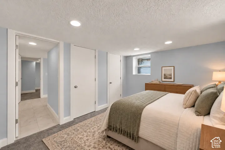 Recessed ceiling lighting, light blue wall paint, white trim, window with frosted glass, and tile flooring in the hallway