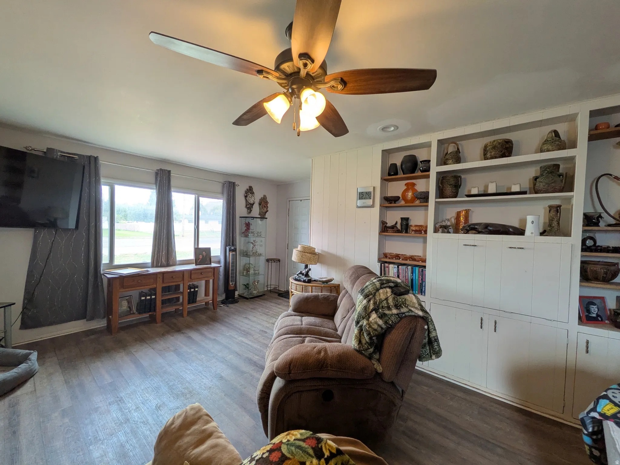 Wood-finish flooring, ceiling fan with light fixture, recessed lighting, built-in shelving, and multiple windows
