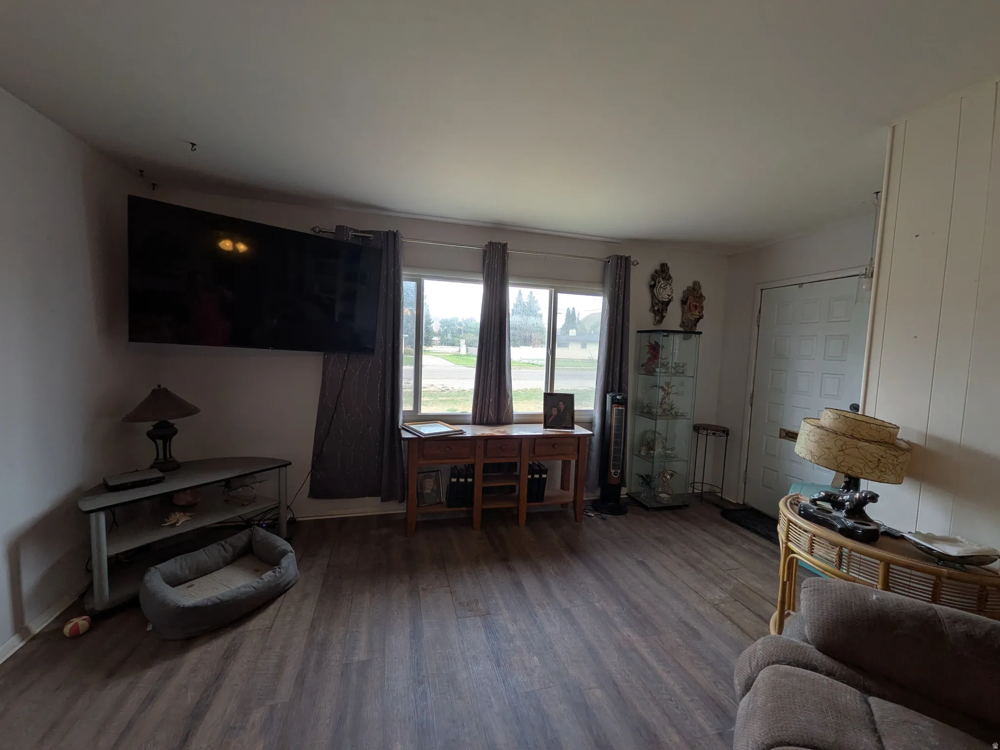 Wood-finish flooring, multiple windows with drapes, and a paneled entry door