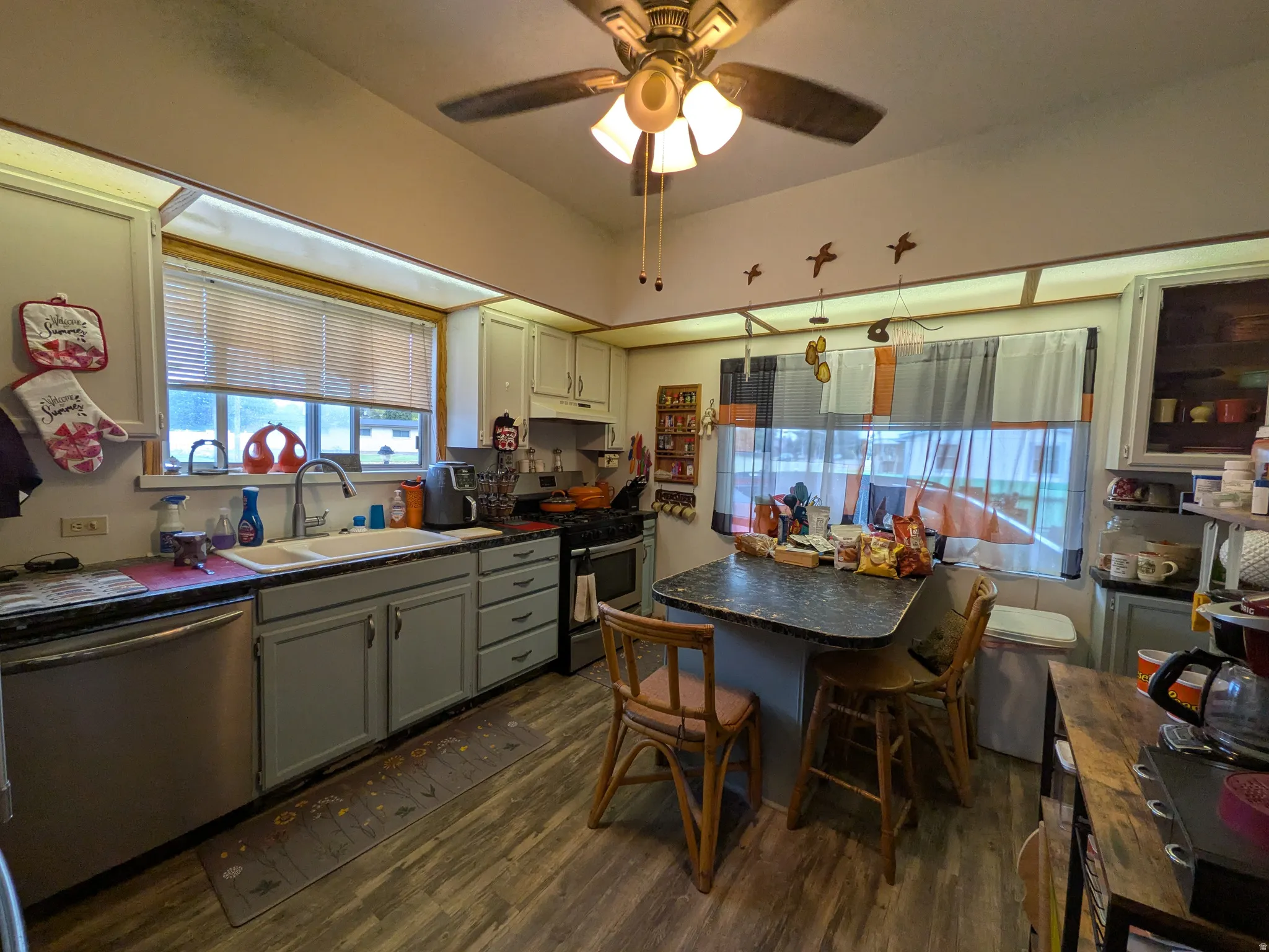 Kitchen featuring wood-finish flooring, recessed lighting, a ceiling fan, light-toned cabinetry, and a built-in island with seating